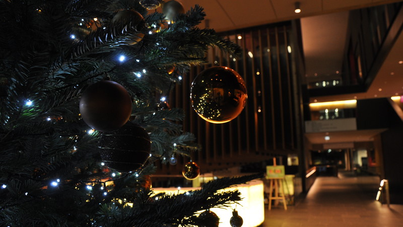 Close up of a decorated Christmas tree on the left, on the right you can see along the corridor in the John Henry Brookes Building from reception towards the Terrace